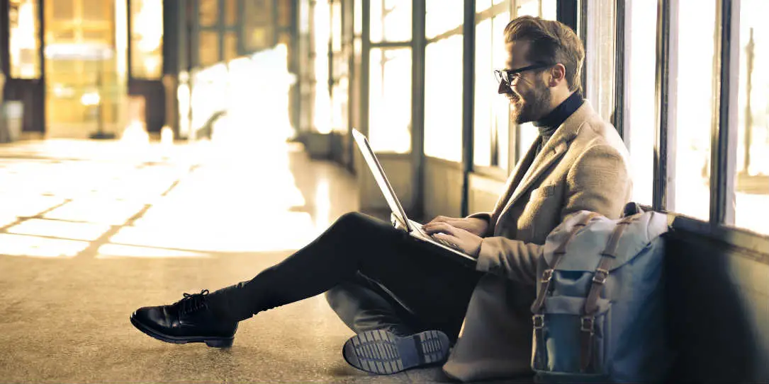 Man on laptop sitting on floor of airport