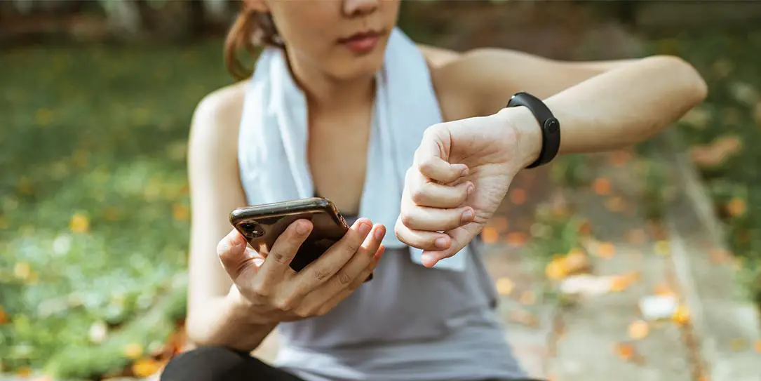 Woman with smartphone and fitness tracker wearable tech