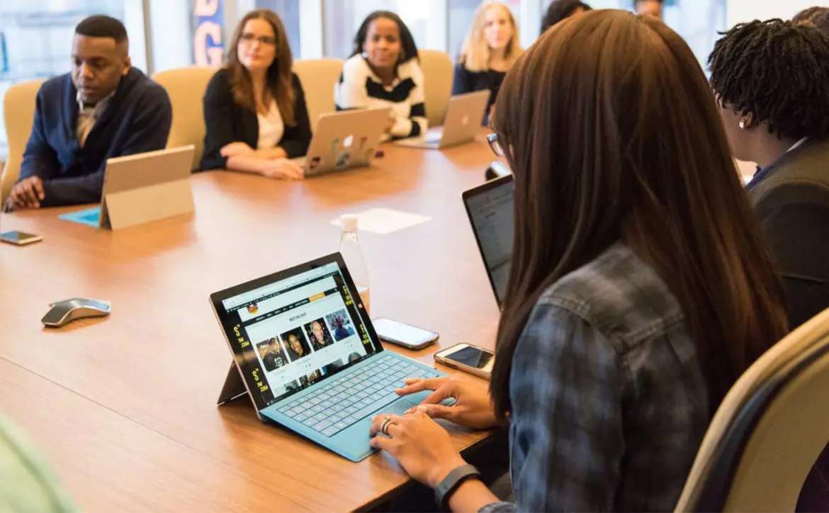 woman on laptop at conference table with other people