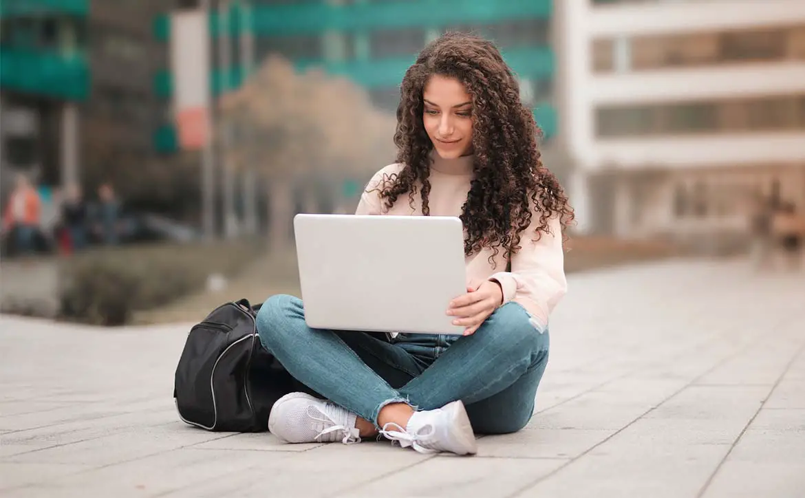 online learning student laptop sitting outside hero