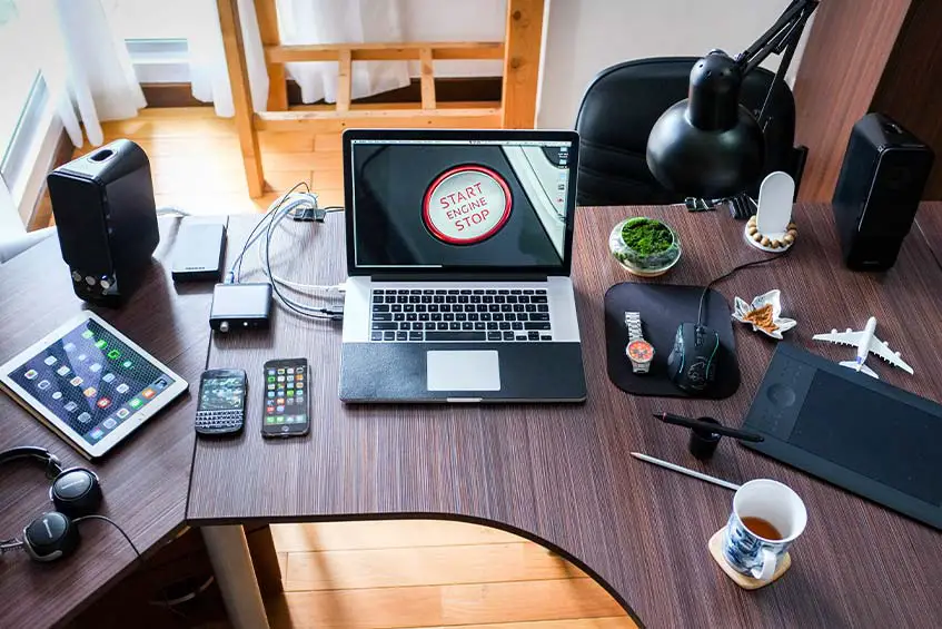 desk with laptop, smartphones, tablets, and other work-related technology
